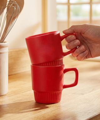 Two red Barista Stackable Coffee Mugs in a kitchen setting.